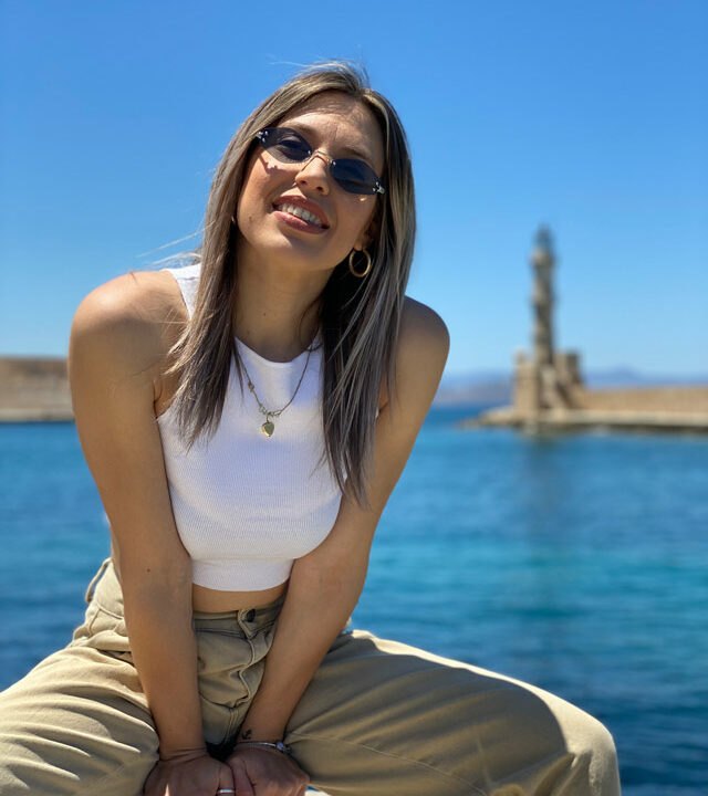 Portrait of a woman with background the lighthouse of Chania
